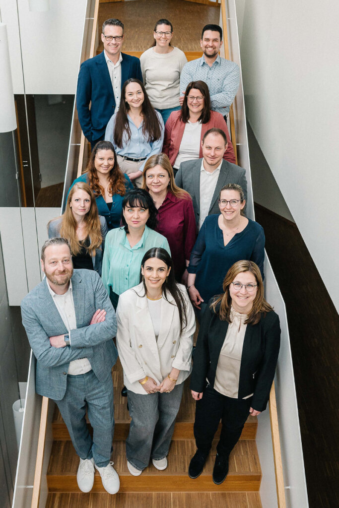 Das Team der Kanzlei Stiefvater & Walk steht gruppiert auf einer Treppe und blickt lächelnd in die Kamera