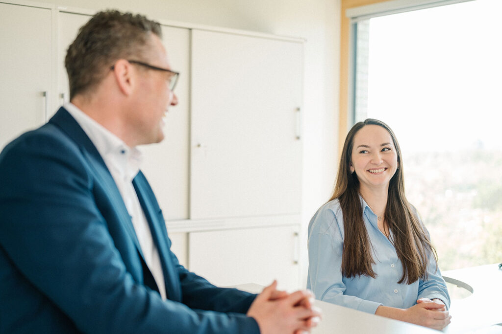 Zwei Mitarbeitende im Gespräch – eine junge Frau lächelt ihren Kollegen freundlich an